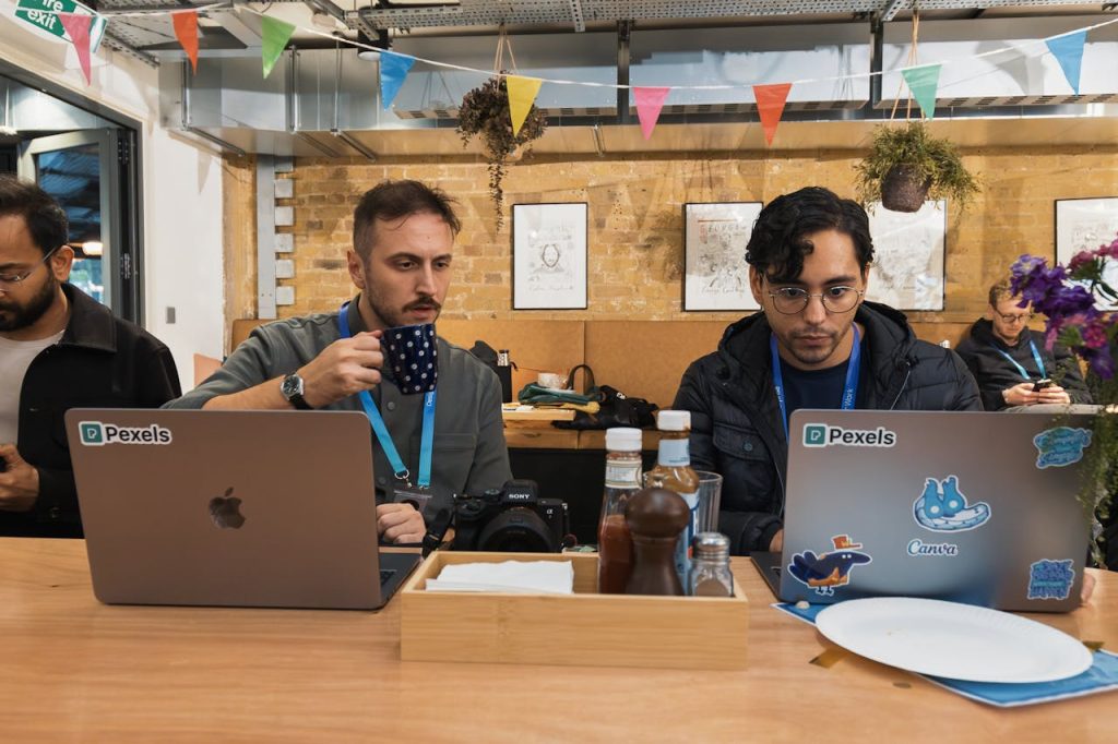 Young professionals working together in a modern cafe setting, focused on laptops.